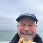 A man smiling and eating a pasty in Cornwall